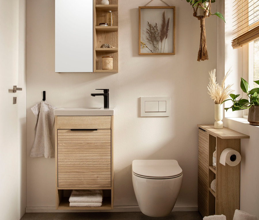 Badezimmer mit »Mads« Waschtisch, Spiegelschrank, Toilette und Holzmöbeln.