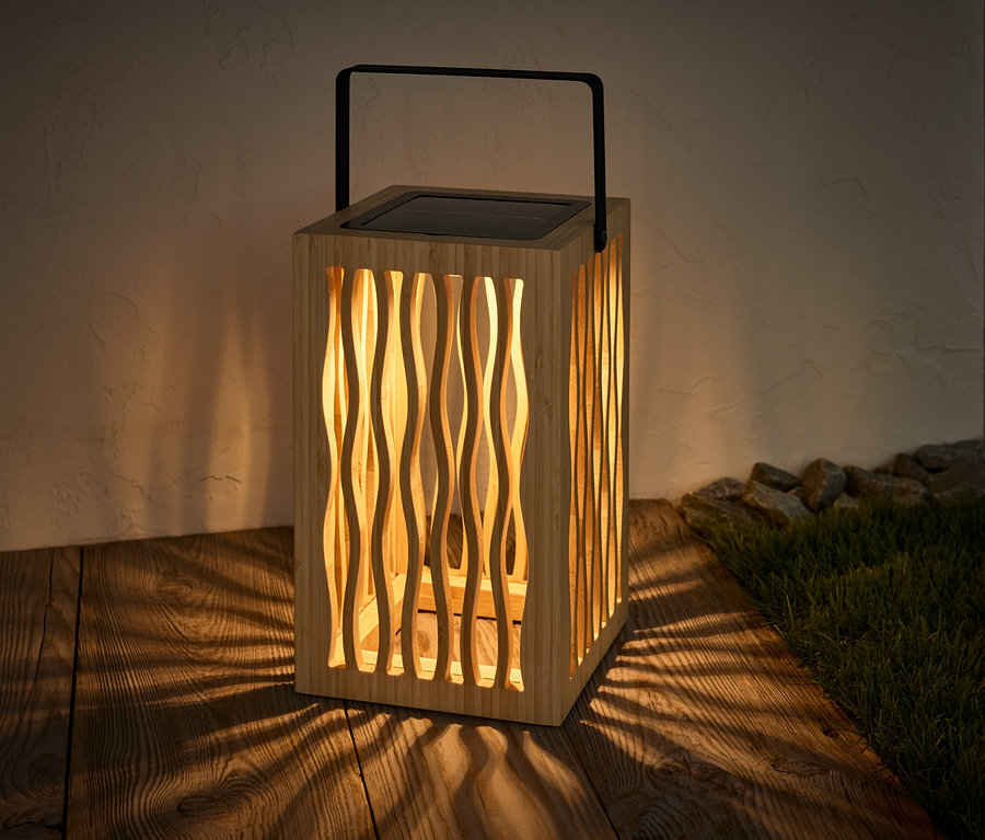 Eine Solar-Laterne steht auf einem Holzboden und wirft einen Schatten.