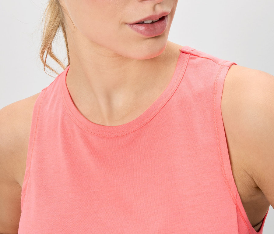 Nahaufnahme einer Frau, die ein korallfarbenes Tanktop trägt.