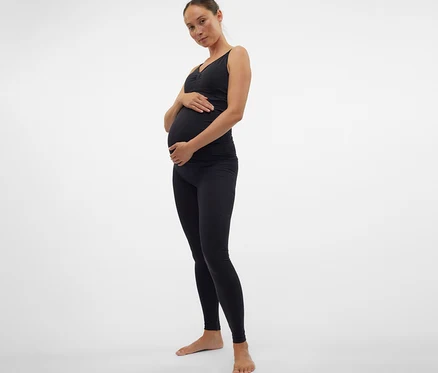 Schwangere Frau in schwarzem Top und MAMALICIOUS Skinny Leggins »MLTIA JEANNE« hält ihren Bauch.