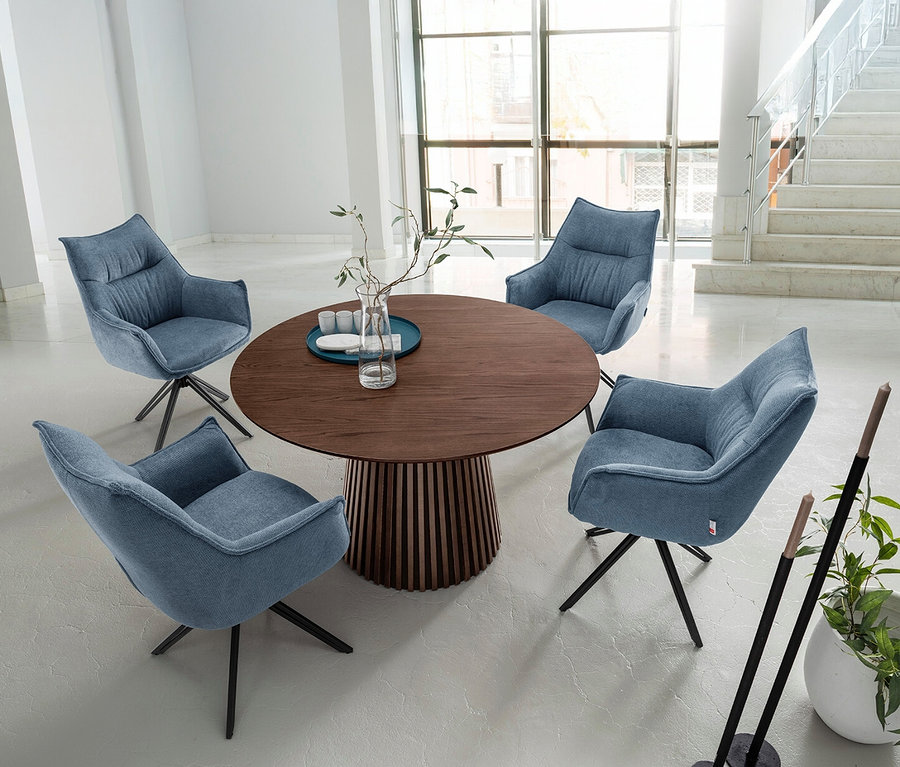 Vier blaue Sessel um einen runden deVries Esstisch »Barletta« Black Oak mit 120 cm Durchmesser.