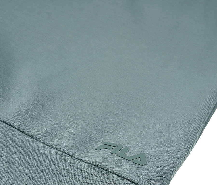 Detailansicht eines hellblaugrünen Kleidungsstücks mit dem FILA-Logo.