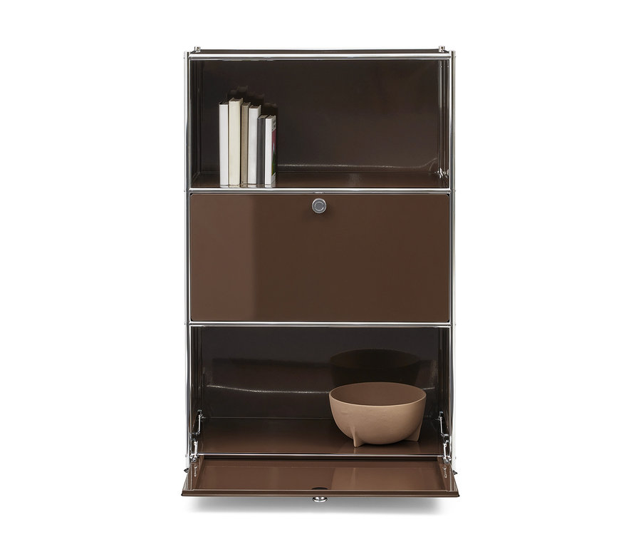 Brauner Modulschrank mit Chromakzenten. Das obere Fach enthält Bücher, das mittlere Fach ist eine geschlossene Tür mit Schloss, und das untere Fach hat eine geöffnete Tür, die eine hellbraune Schale zeigt.