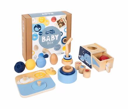 small foot Baby-Box, 10–12 Monate: Eine offene Kartonbox mit verschiedenen Holz- und Silikonspielzeugen, darunter Stapeltürme, ein Steckwürfel mit Walmotiven, ein Puzzle und drei strukturierte Bälle.