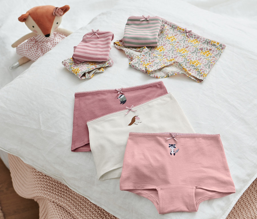 Auf einem weißen Kissen liegen 7 Mädchen-Pantys und ein Plüschfuchs.