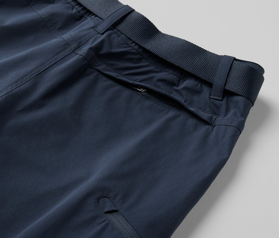 Detail einer blauen 2-in-1-Funktionshose mit Reissverschlusstaschen und Gürtel.