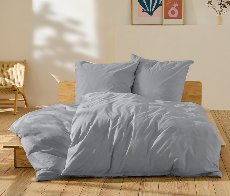 Graue Perkal-Bettwäsche in Normal- und Übergröße auf einem Bett.