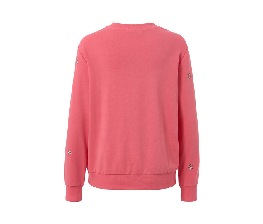 Detailansicht eines rosafarbenen, bestickten Sweatshirts mit Blumenstickereien an den Ärmeln.