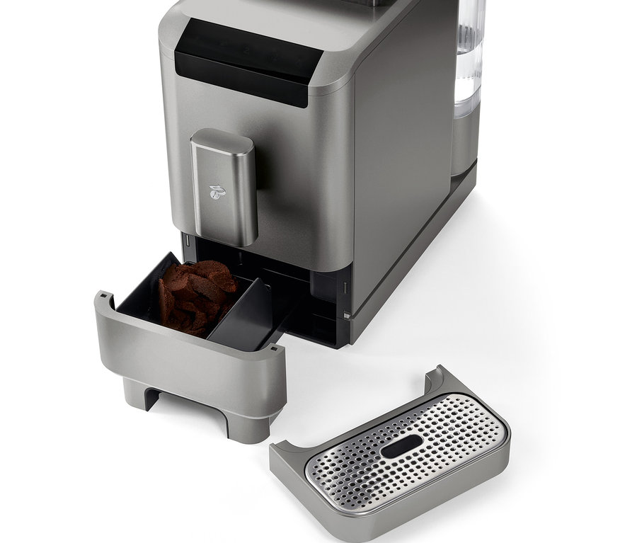 Detailaufnahme des »Esperto2 Caffè« Kaffeevollautomaten in Titanium Silver mit entnommenem Kaffeesatzbehälter und Tropfschale.