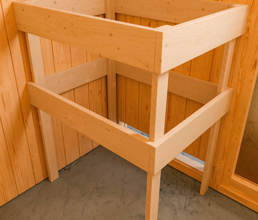 Eine Holzkonstruktion mit Regalen steht in einer Ecke eines Raumes mit Holzvertäfelung.