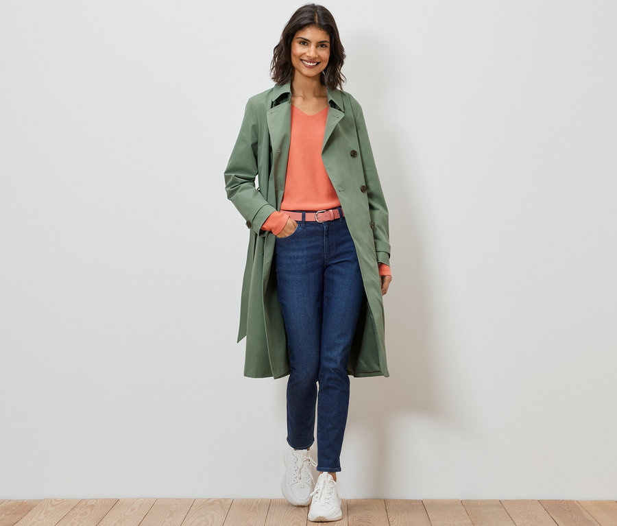 Frau geht und trägt einen hellgrünen Trenchcoat.