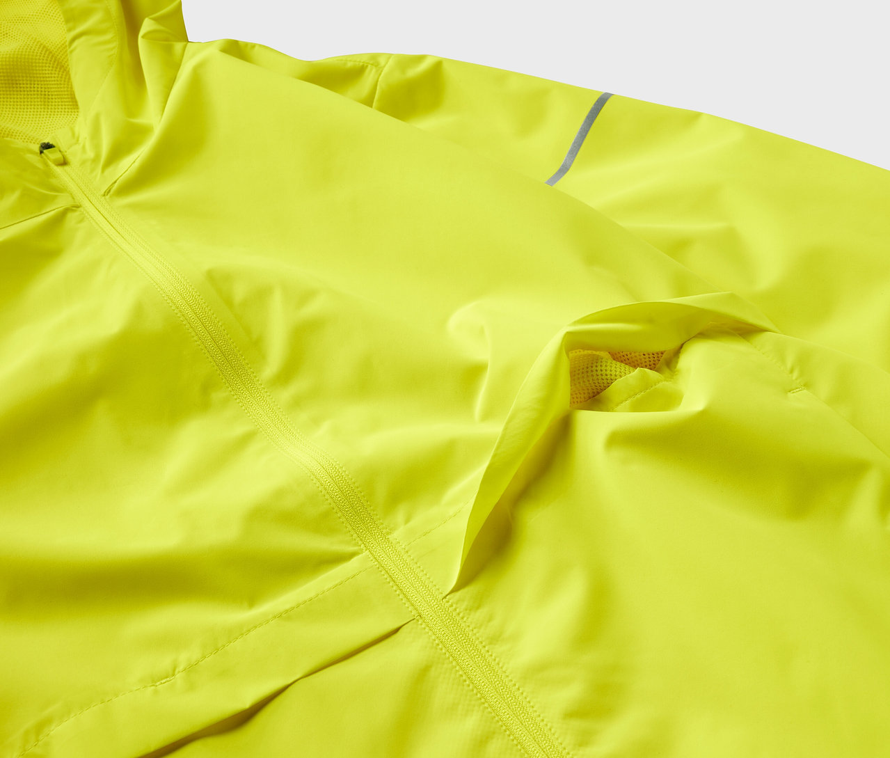 Detailaufnahme einer gelben Jacke mit Textur und Reißverschluss.