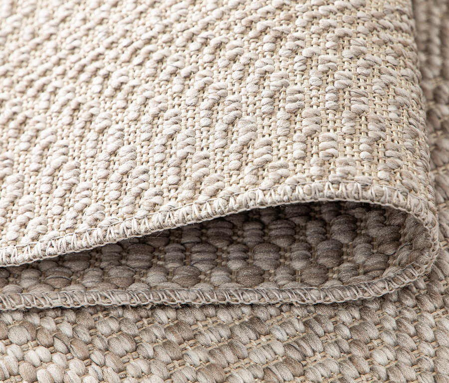 Detailaufnahme eines beigen Teppichs »Twine« mit feiner Textur und Kante.