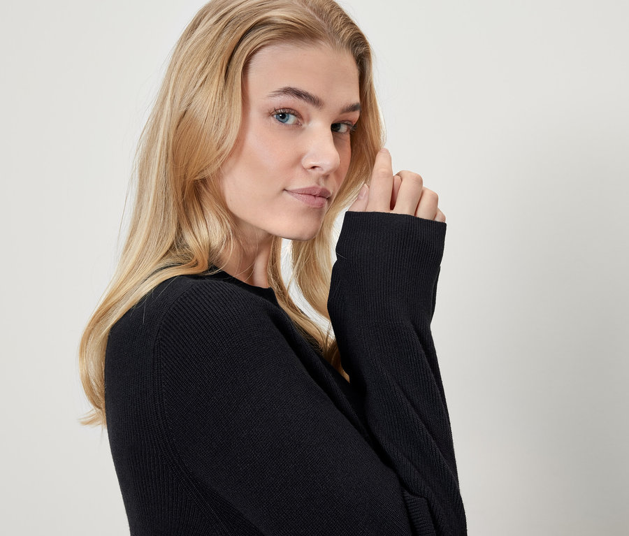 Porträt einer blonden Frau in einem schwarzen Pullover.