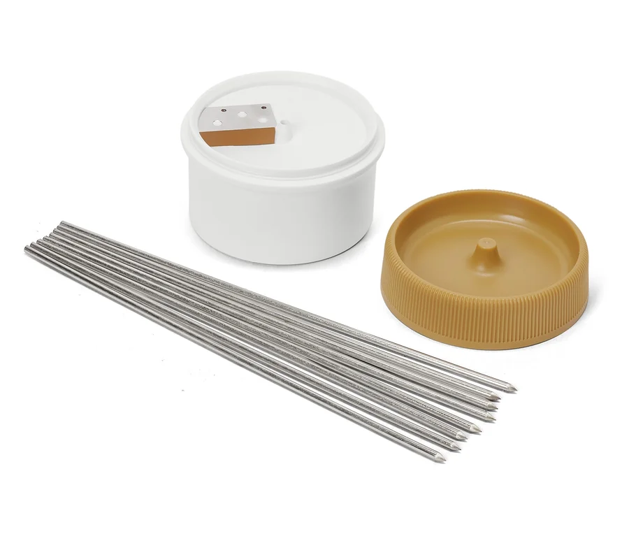 Kerzenherstellungsset mit weißem Behälter, braunem Deckel und Metallkerzendochten.