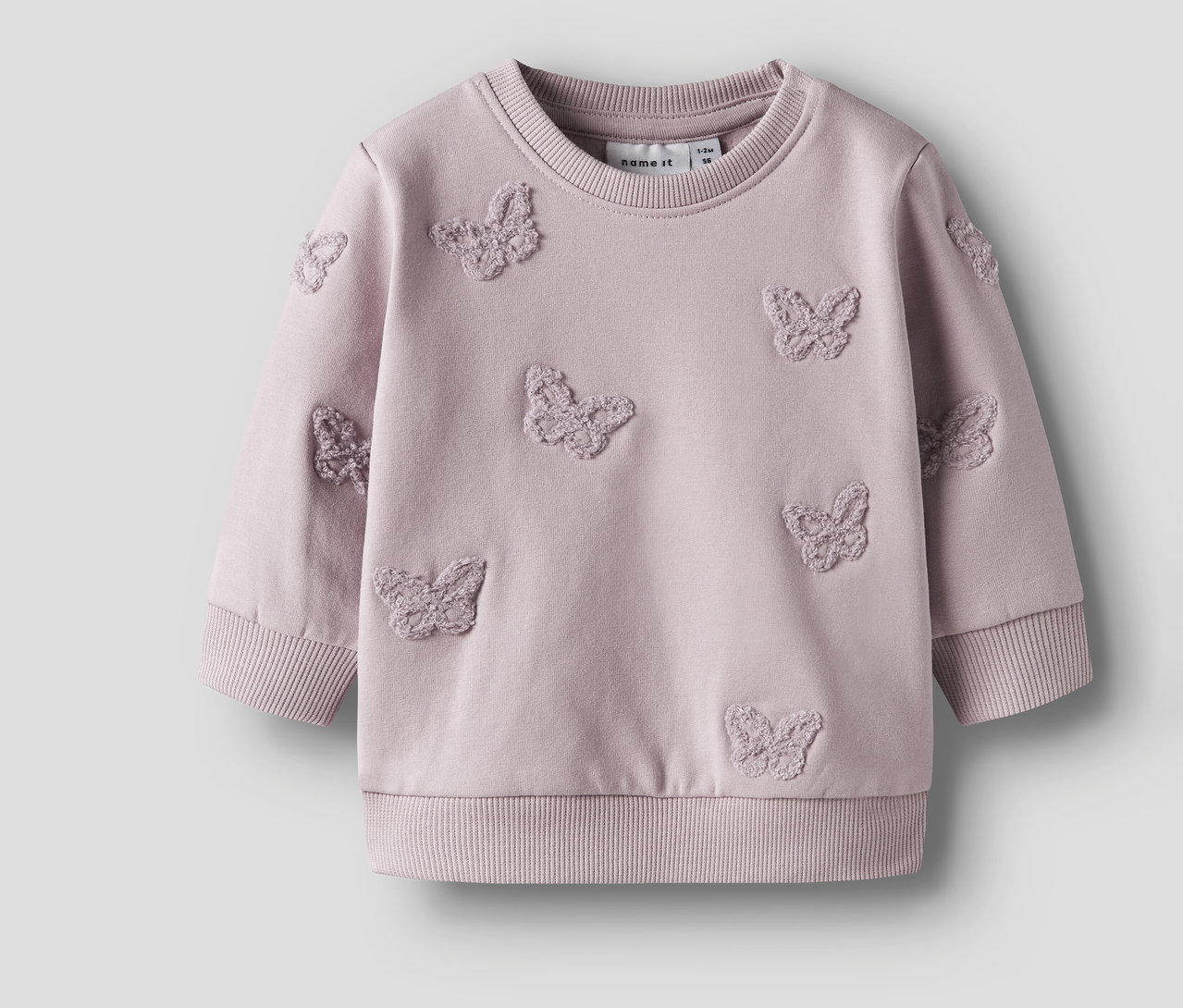 Ein lilafarbenes NAME IT Baby-Sweatshirt mit aufgenähten Schmetterlingen ist auf einem neutralen Hintergrund zu sehen.