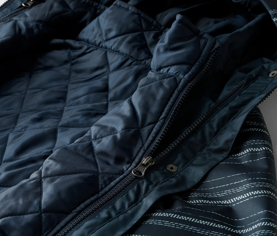 Nahaufnahme einer marineblauen Jacke mit Reißverschluss und gestepptem Innenfutter.