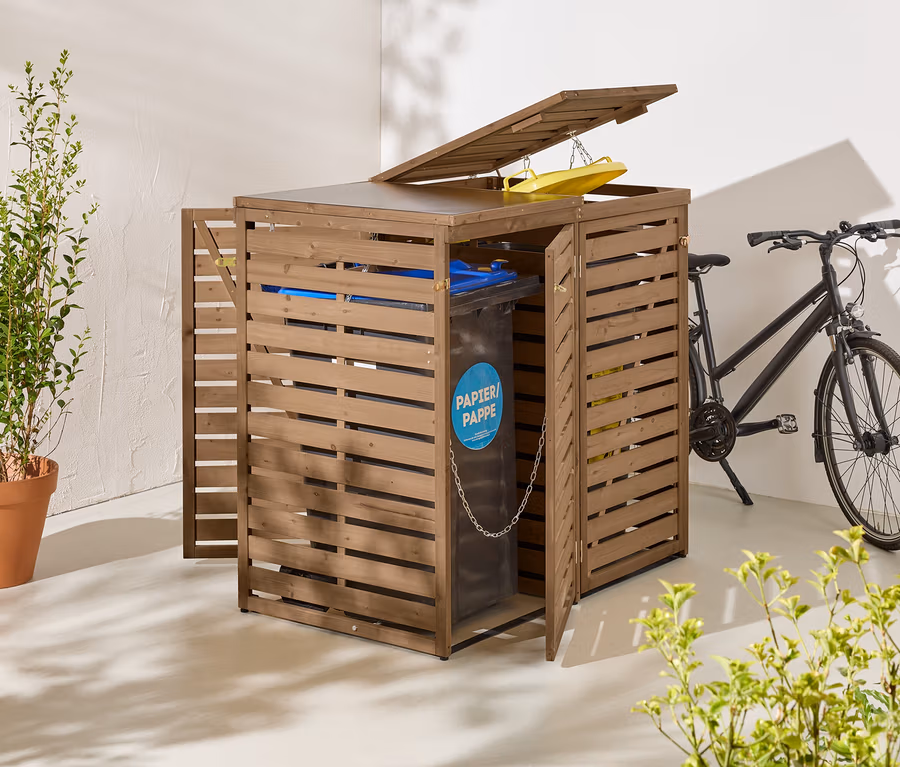Eine braune Mülltonnenbox aus Holz mit geöffneten Türen und Deckel steht neben einem schwarzen Fahrrad.