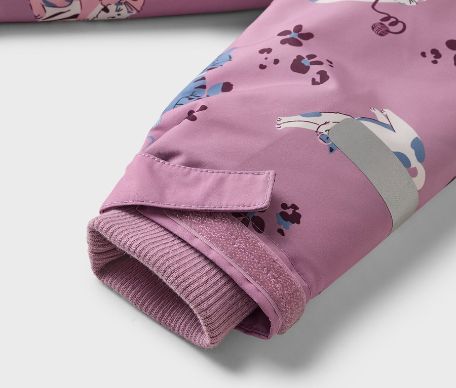 Nahaufnahme des Ärmels einer lila Jacke mit Katzenmuster, geripptem Bündchen, Klettverschluss und reflektierendem Streifen.