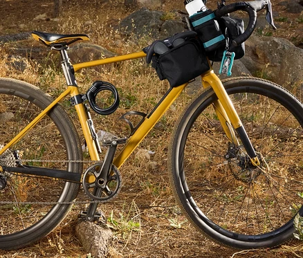 Gelbes Fahrrad mit schwarzen Taschen und Zubehör im Wald.