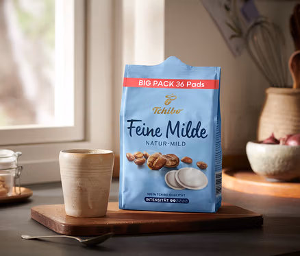 Eine Packung Feine Milde Pads - 36 Pads steht neben einer Tasse auf einem Holztablett.