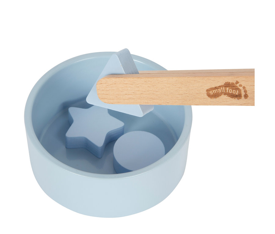 Ein hellblaues Schälchen enthält hellblaue Holzformen: einen Stern und einen Kreis. Eine Holzpinzette, Teil des small foot Montessori-Bundle 1, hält ein hellblaues Dreieck über dem Schälchen.