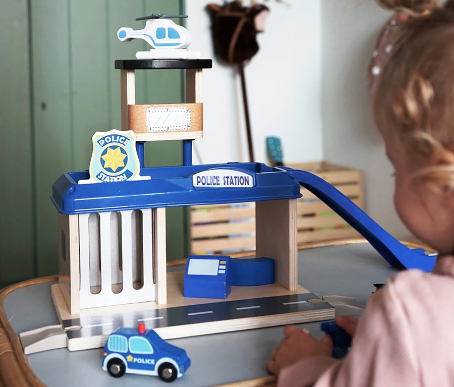 Kind spielt mit small foot Polizeiwache mit Zubehör, inklusive Polizeiauto und Helikopter.