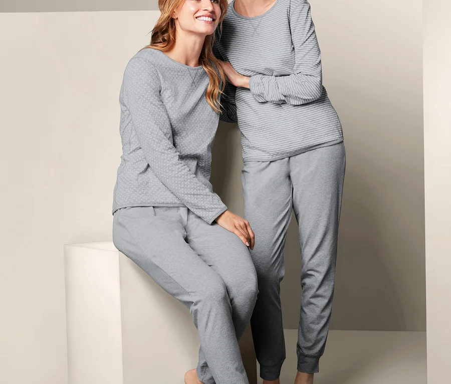Zwei Frauen posieren in grauen Wende-Pyjamas.