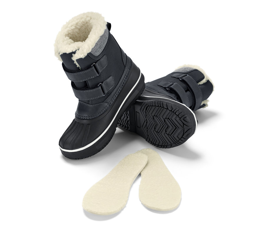 Schwarze Kinder-Allwetterstiefel liegen seitlich mit Einlegesohlen.