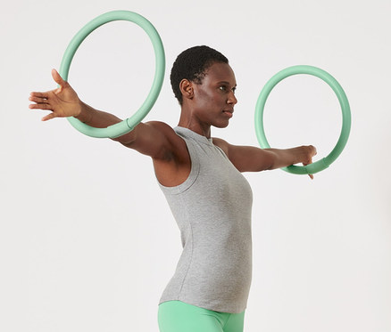 Frau trainiert mit 2 Arm-Trainingsreifen.