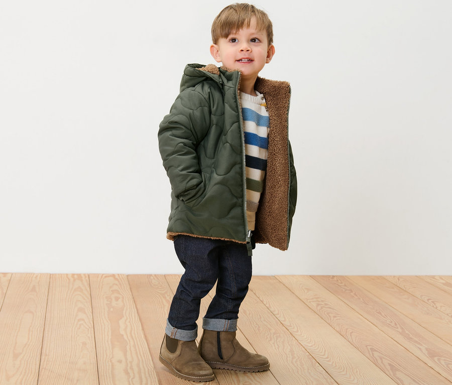 Junge steht und trägt eine Kinder-Wendejacke.