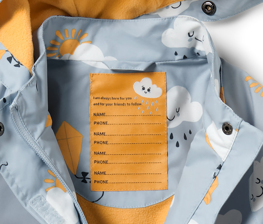 Detail einer hellblauen Kleinkind-Thermo-Regenjacke mit Alloverprint von Wolken, Sonne und Drachen.
