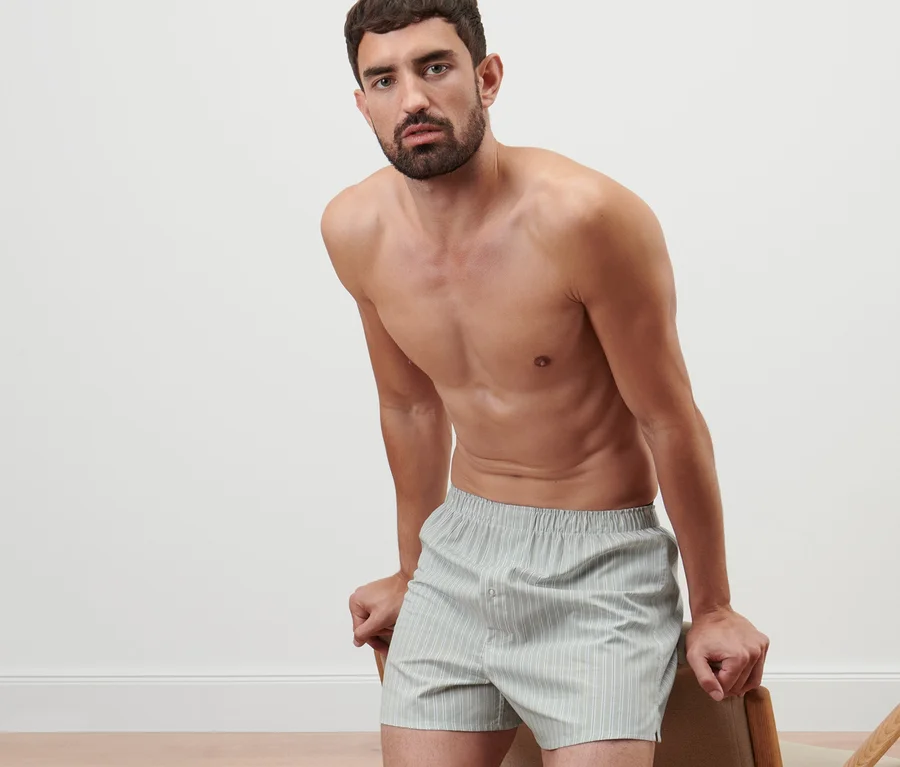 Mann, der sich an einen Stuhl lehnt, trägt 2 Web-Boxershorts.