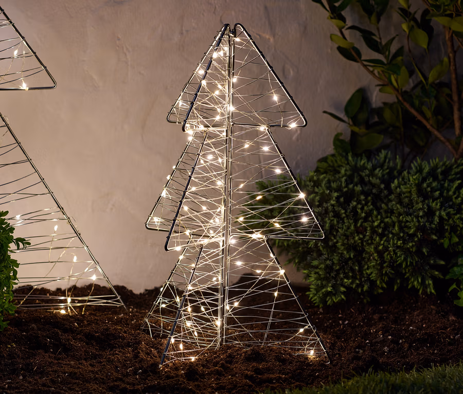 Zwei LED-Outdoor-Tannen, faltbar, ca. 45 cm, stehen auf dem Boden neben Büschen.