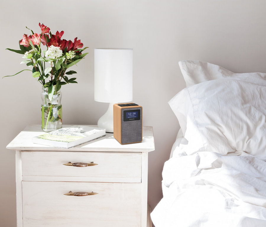 Blumen in Vase, Lampe und Philips DAB-Radio »TAR5005« auf weißem Nachttisch neben Bett.