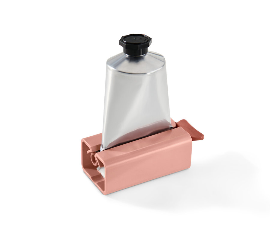 Eine silberne Tube in einem rosa Tubenpresser.