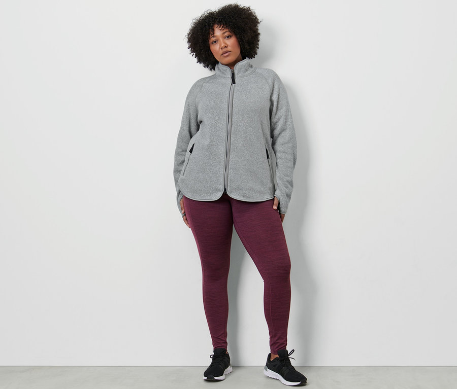 Frau trägt Sporttight und hellgraue Strickfleece-Jacke.