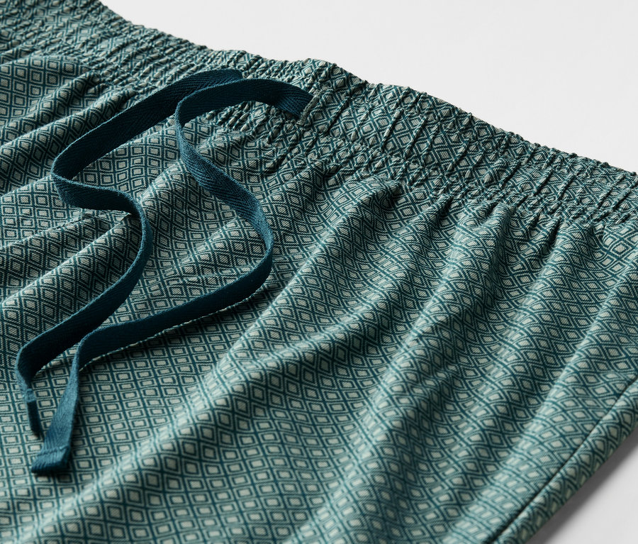 Detail einer grünen, gemusterten Pyjamahose mit elastischem Bund und Kordelzug.