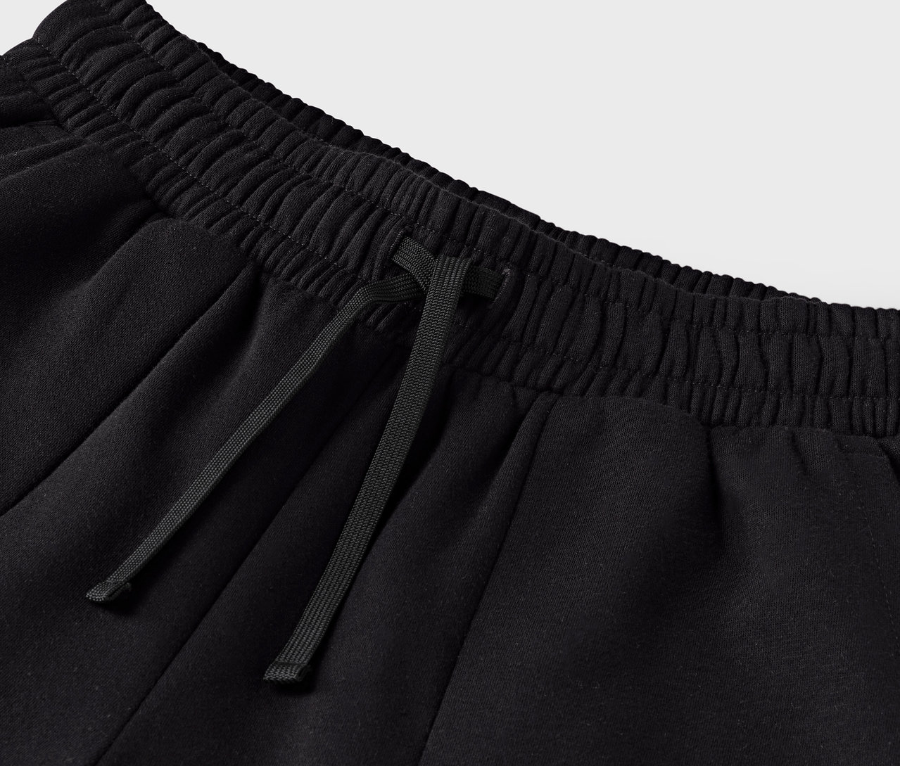 Detailaufnahme einer schwarzen Jogginghose mit Kordelzug in der Taille.