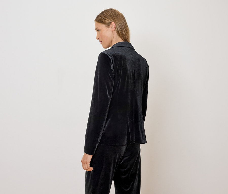 Frau trägt einen Samtblazer und eine Hose.