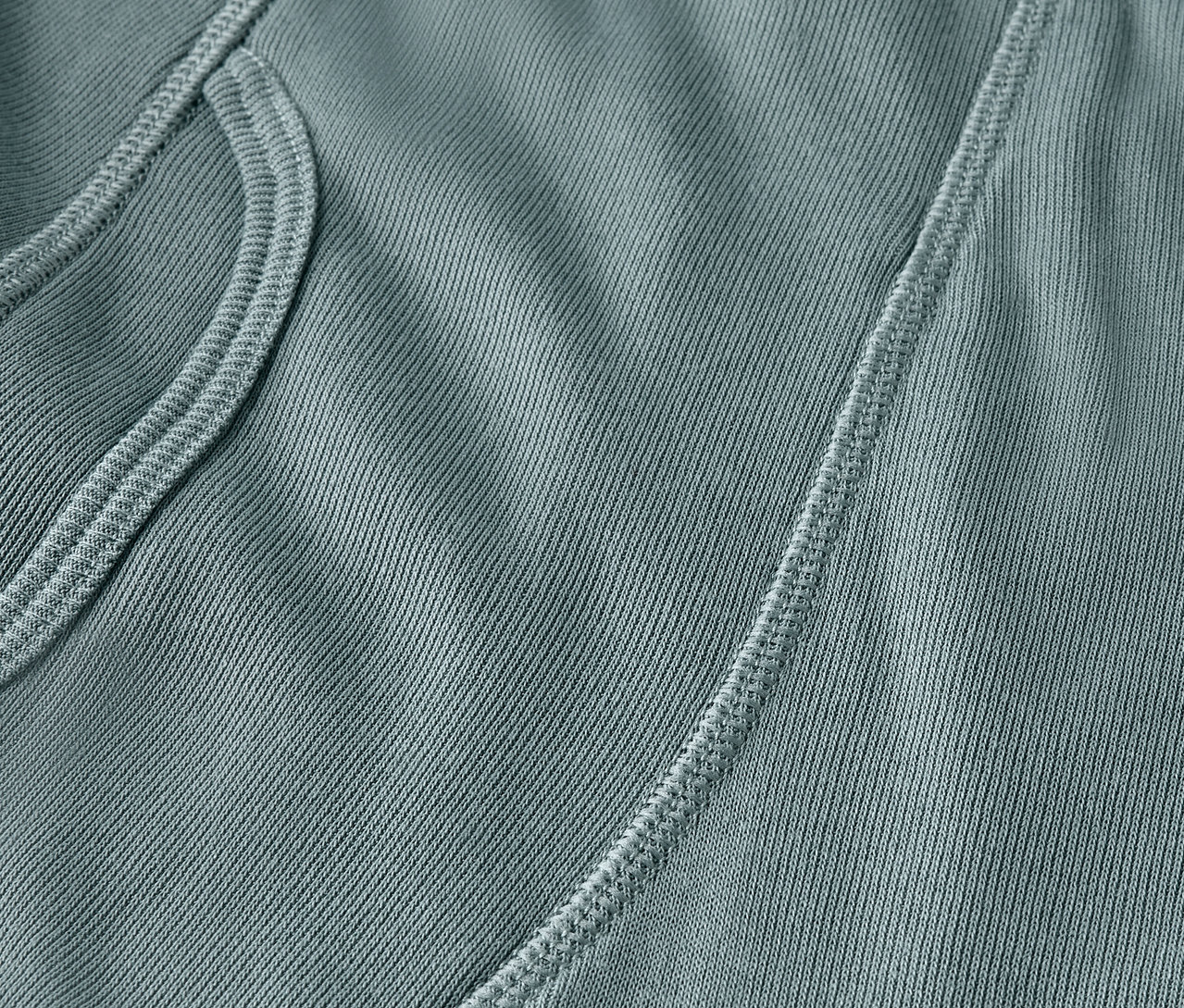 Detailaufnahme eines blaugrünen Stoffes mit Tasche und Naht.