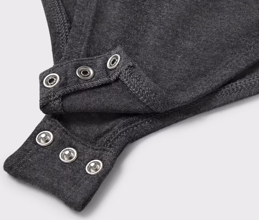 Detailaufnahme eines grauen Bodys mit Druckknöpfen.