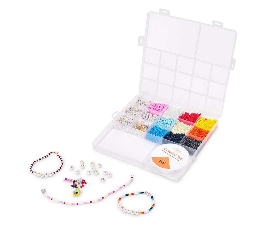 Geöffnete, transparente Box mit bunten Perlen. Mehrere fertige Armbänder und lose Buchstabenperlen liegen daneben.