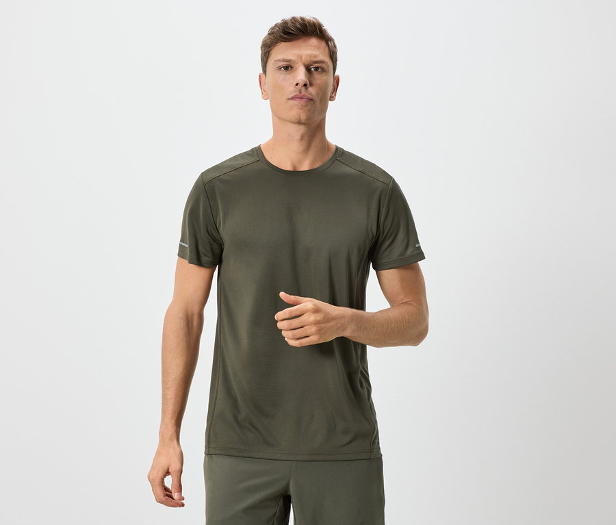 Mann in olivgrünem T-Shirt und Shorts vor neutralem Hintergrund.