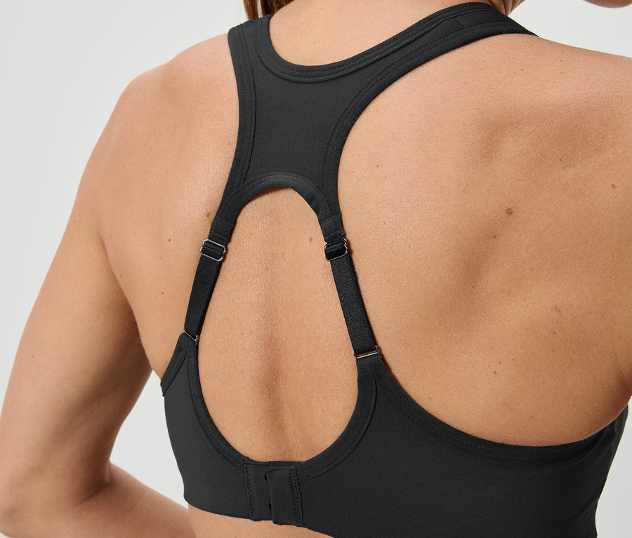 Nahaufnahme der Rückseite einer Frau, die einen schwarzen Sport-BH mit verstellbaren Trägern trägt.