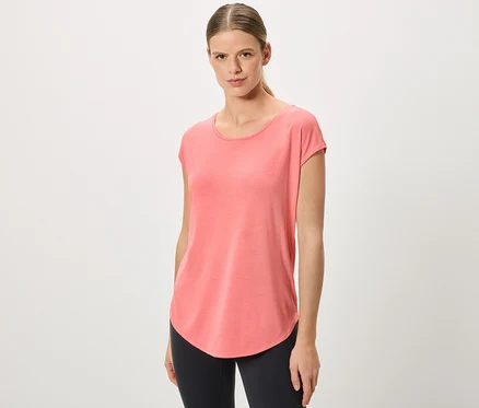 Frau mit Pferdeschwanz trägt ein korallfarbenes T-Shirt und schwarze Leggings.