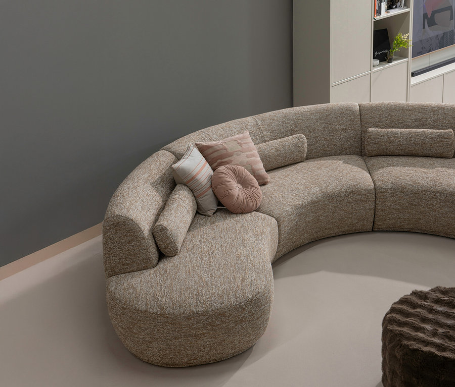 Beiges, segmentiertes Sofa mit Kissen. Im Vordergrund steht ein brauner, niedriger WOOOD Hocker »Olven«.