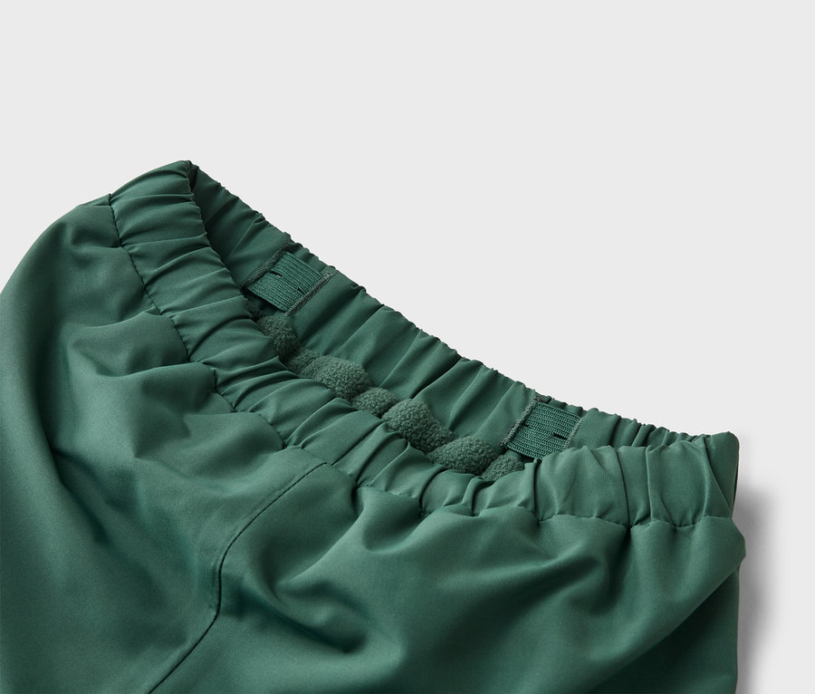 Detailaufnahme vom Bund einer grünen Hose mit Gummizug und Kordel.