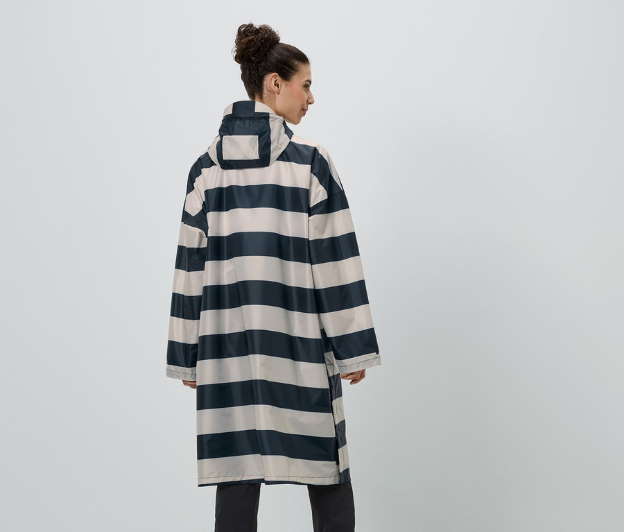 Eine Frau mit Dutt trägt einen gestreiften Regenmantel in Marineblau und Beige, von hinten gesehen.