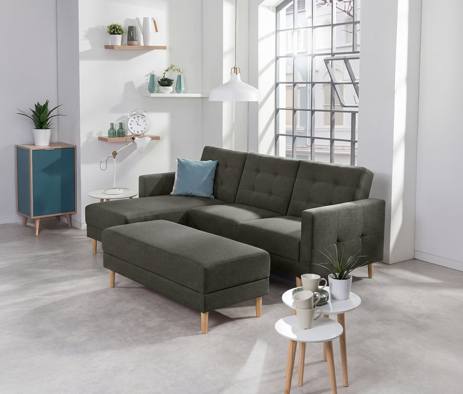 Dunkelgraues Federkern-Eckschlafsofa «Just Relax» mit Stauraumbank und hellblauem Kissen in einem modernen Wohnzimmer mit Regalen und teal-farbenem Schrank.